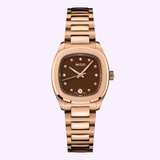A Mido Multifort TV 28 Quartz M0491103329600 wristwatch by Mido Watches, featuring a rose-gold-tone PVD case, brown dial with diamond hour markers, date display at 6 o’clock, and a metal bracelet band, photographed on a light purple background.