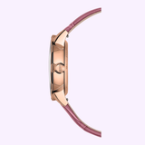 Side view of the Mido Watch Rainflower Night M0432073610600 by Mido Watches, featuring a rose gold case and pink leather strap, highlighting its slim curved profile against a light lavender background.