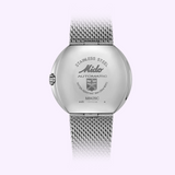 The metal case back of a Mido Watches Commander 1959 M842942511 watch with a mesh bracelet, featuring engraved text including Stainless Steel, Automatic, and Water-Resistant 5bar.