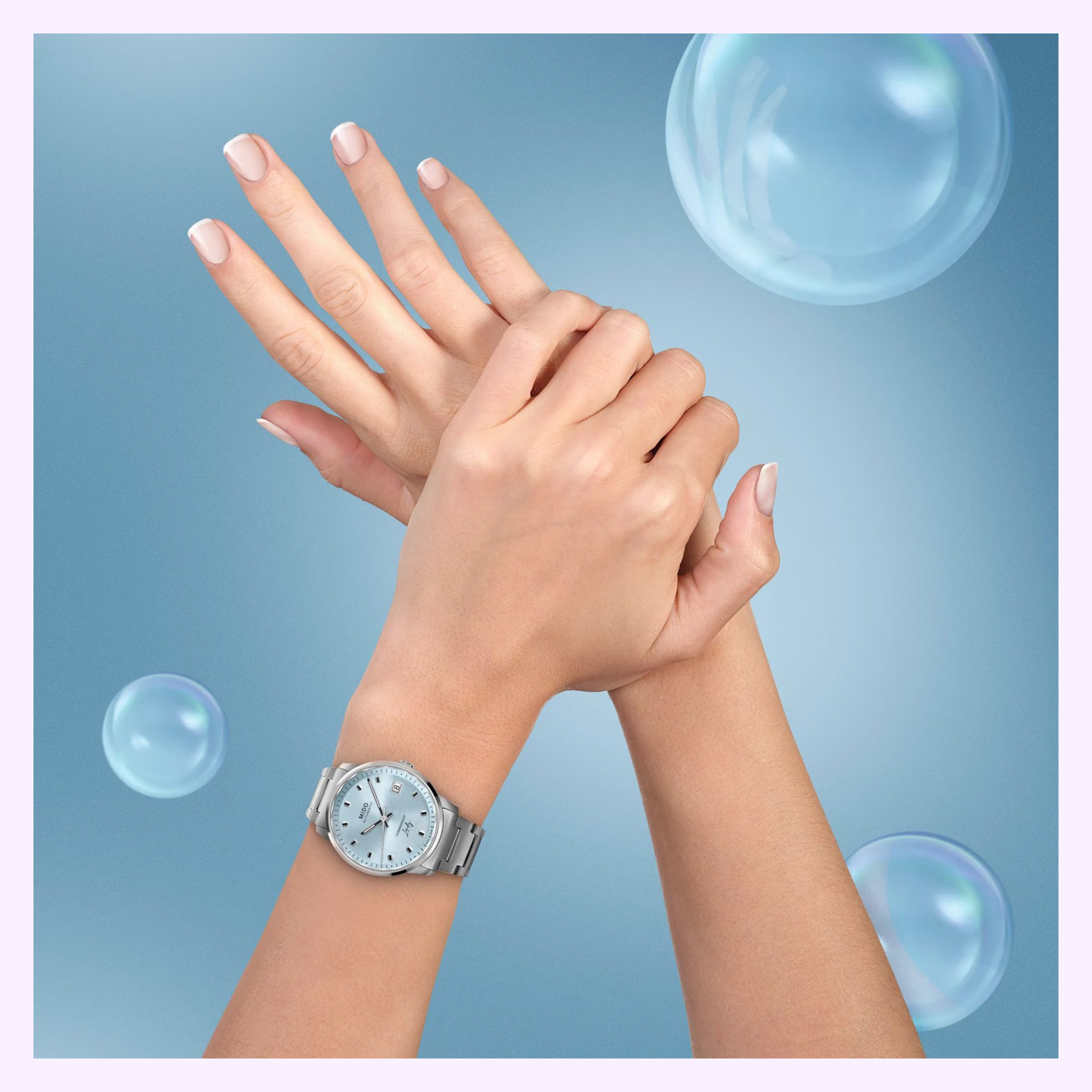 A close-up of two hands with manicured nails crossed, one wearing the Mido Watches Commander Lady M0212071104100. The background is blue with translucent bubbles, highlighting the elegance of this Swiss timepiece from Mido Watches.
