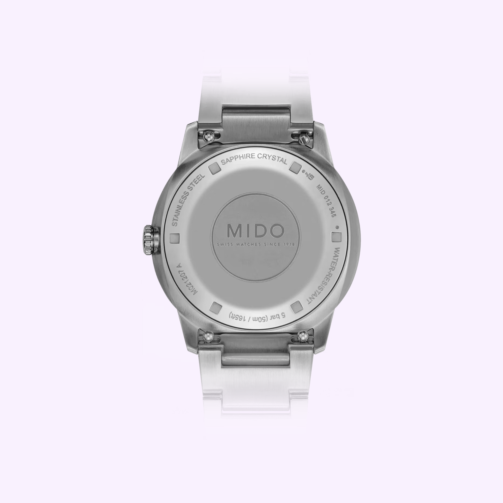 Back of the Mido Watches Commander Lady M0212071104100, with stainless steel case back, sapphire crystal inscription, 5 bar/50m water resistance, and white bracelet, shown on a light lavender background.