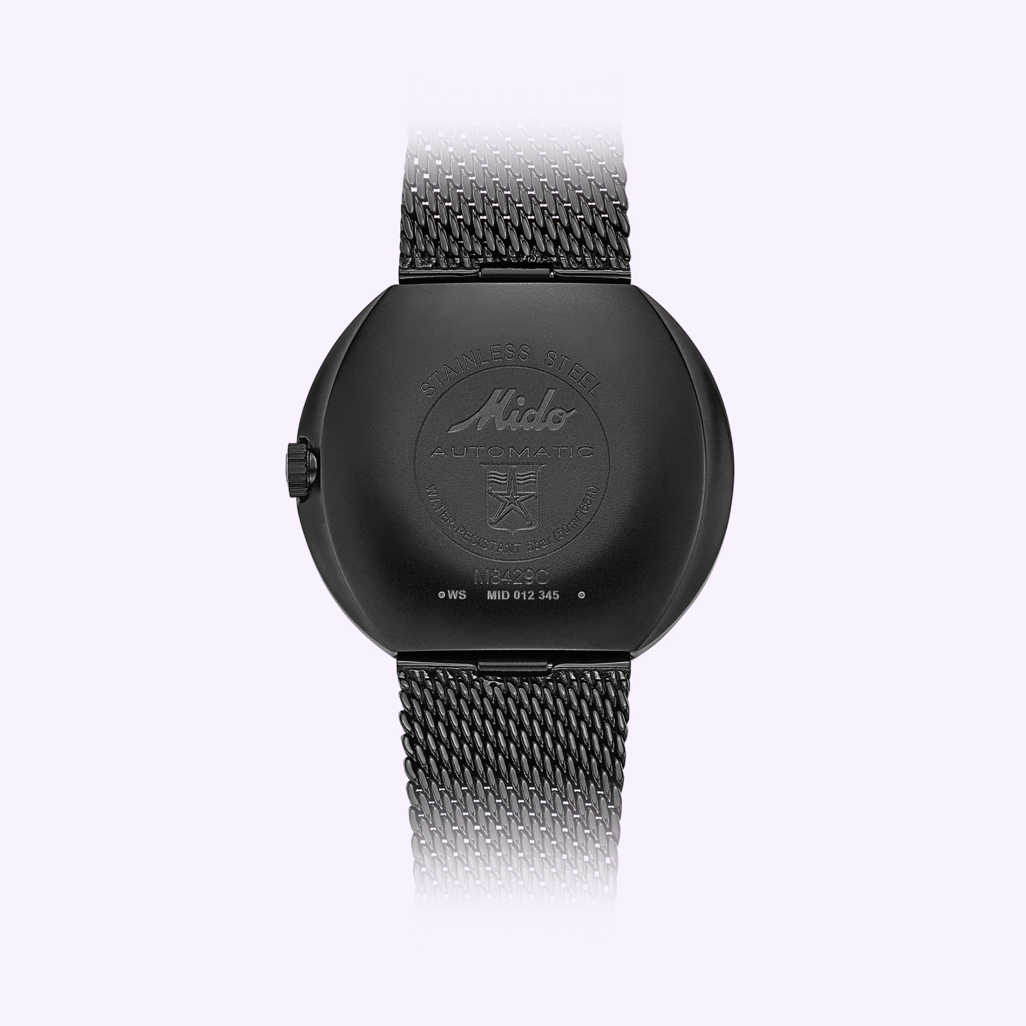 The Mido Watches Commander Shade M842942511 in black stainless steel is shown from the back, highlighting the brand logo, automatic movement text, and its metal mesh strap against a light purple background.