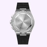 The back view of the Mido Watches Multifort 8 Chronograph Quartz (M0555171705100) highlights its stainless steel case with engraved branding and a black textured rubber strap, set against a light purple background.