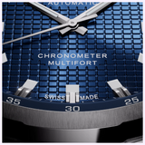 Close-up of a Mido Watches Multifort TV Big Date Chronometer M0495671104100 featuring a blue square-patterned dial with silver hands, hour markers, and the text CHRONOMETER, MULTIFORT, and SWISS MADE.