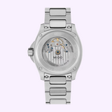 The case back of a silver-tone metal link Mido Watches Multifort TV Big Date Chronometer M0495671105100 showing the intricate mechanical movement through a clear exhibition window.