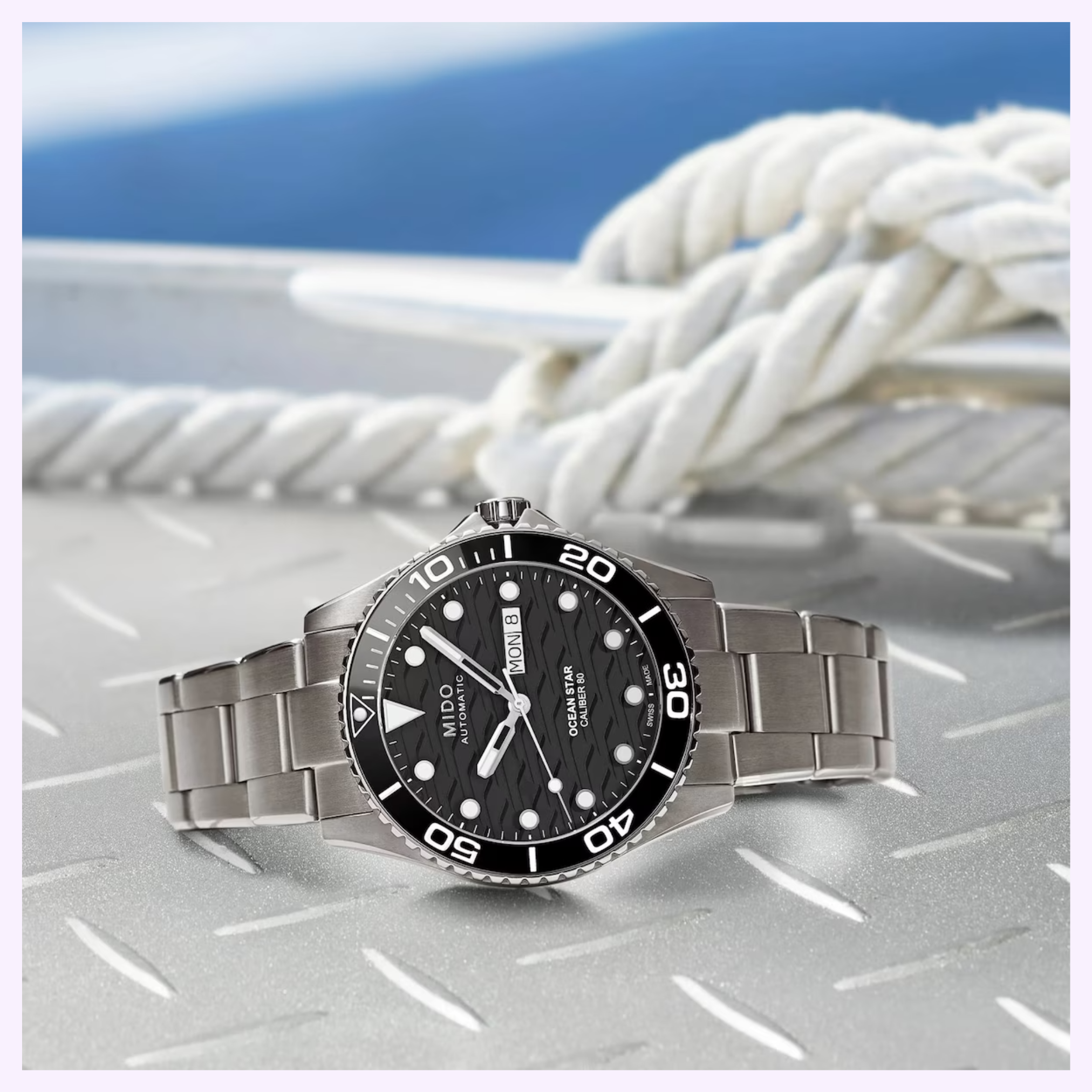 Mido Watches Ocean Star 200C Titanium M0424304405100 diver's watch with black dial and rotating bezel on a steel bracelet, featuring Swiss automatic movement, displayed on metal with white nautical rope in the background.