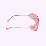 Side view of Miu Miu Sunglasses 0MU A51S 5AK90Y75 with pink lenses, gold arms, and gold decorative text, set against a light purple background—an elegant addition to any designer eyewear collection.