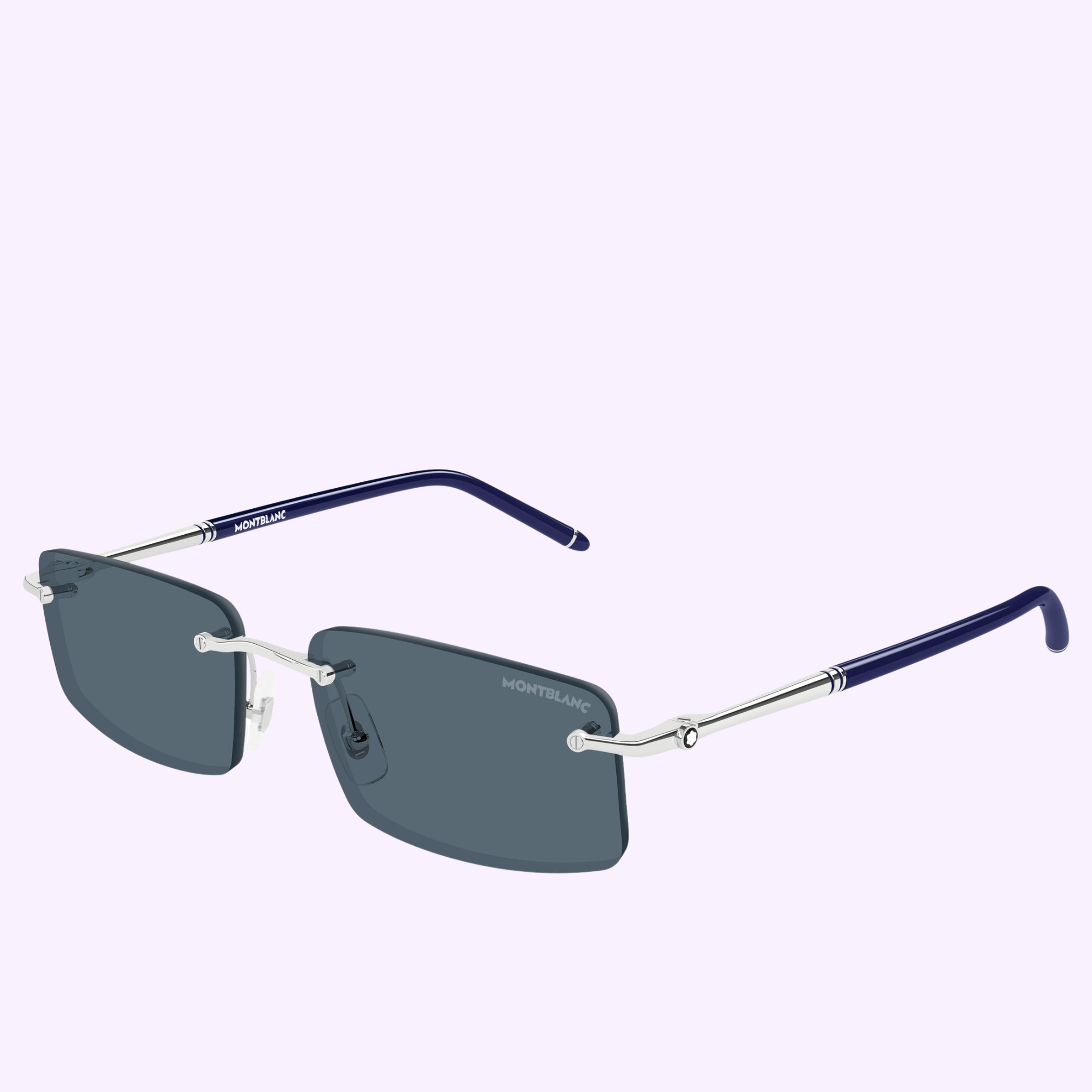 The Montblanc Sunglasses MB0443S-003 56 feature a rectangular rimless design with dark lenses, silver bridge and temples, navy blue earpieces, and the Montblanc logo on the lens and arm, shown against a light lavender background.
