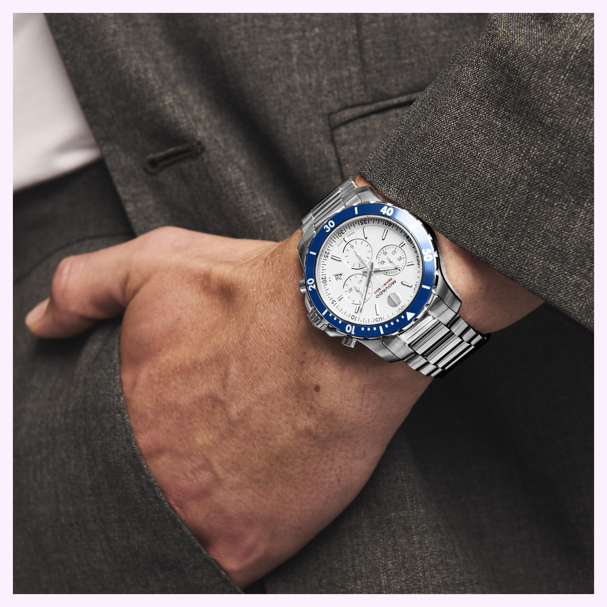 A person in a gray suit with their hand in their pocket, wearing a Movado Watches Series 800 Chronograph 2600195—silver with a blue bezel and white multi-subdial dial.