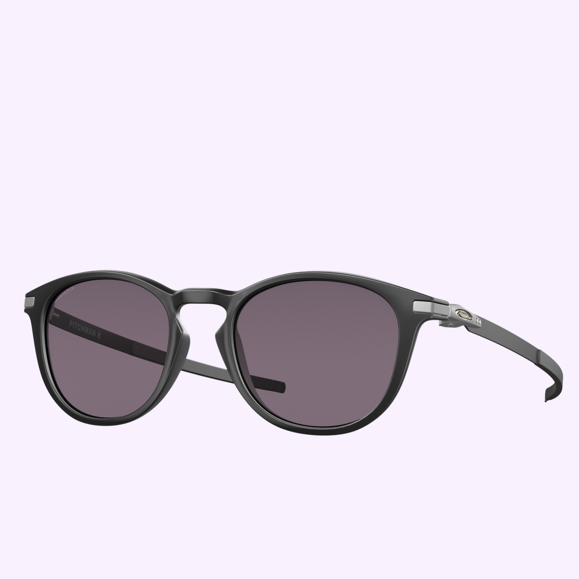 Oakley Sunglasses 0OO9439 94390150, featuring a black round frame with dark tinted lenses, are displayed against a light purple background. The frame is accented by a small silver detail near the hinges on both sides.