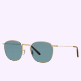 Oliver People OV1285ST 529256 52 Goldsen unisex sunglasses by Oliver People Sunglasses, featuring gold metal thin frames and blue-tinted rectangular lenses, photographed on a light purple background.