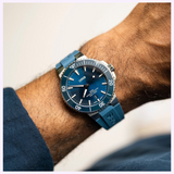 Blue Oris Watches Aquis Date dive watch with a matching rubber strap on a person’s wrist.