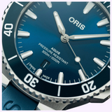 Close-up of a blue Oris Watches Aquis Date dive watch with a dark blue rotating bezel, luminous markers, a date window at the six o’clock position, and a matching blue strap.