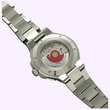 The stainless steel case back of an Oris Watches Aquis Date, revealing an automatic movement through a circular exhibition window with a distinctive red rotor.