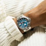 An Oris Watches Aquis Date Upcycle Calibre 400 stainless steel divers watch with a colorful, patterned recycled PET dial worn on a wrist.