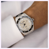 An Oris Watches Divers Date stainless steel dive watch with a black rotating bezel and a beige dial on a person’s wrist.