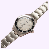 Silver-tone Oris Watches Divers Date analog watch featuring a light-colored dial, black rotating bezel, and a stainless steel link bracelet.