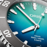 Close-up of an Oris Watches Great Barrier Reef Limited Edition IV watch face with a blue-to-green gradient dial, featuring silver indices, hour and minute hands, and text reading AQUIS 300m / 1000ft 5 DAYS.
