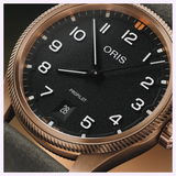 Close-up of an Oris Watches ProPilot Bronze watch featuring a black textured dial, white numerals, and a date display at the six o’clock position.