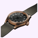 An Oris Watches ProPilot Bronze aviation-inspired watch featuring a black textured dial, white numerals, and a grey suede strap.