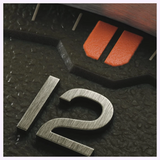 Close-up of an Oris Watches ProPilot Date dial featuring a metallic number 12, a textured black surface, and two orange rectangular markers.
