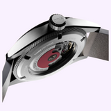 Close-up side view of an Oris Watches ProPilot Date, highlighting the winding crown and a clear case back that reveals the Swiss mechanical watch movement with a red rotor.