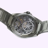 The case back of an Oris Watches ProPilot X Gonzo Edition metallic watch with a transparent exhibition window displaying the complex internal gears and mechanical movement.