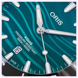 Close-up of an Oris Watches Yangtze Jiangtun Limited Edition watch face in teal with a wavy pattern, silver hands, white indices, a date window showing 16, and text reading AQUIS PRESSURE RESISTANT 300m/1000ft.