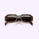 PRADA Sunglasses 0PR 17WSF 20D50Q51 feature a Juniper Tortoise rectangular frame with thick, angular rims and wide arms, showcased from the front against a light pink background—these women’s sunglasses embody the signature elegance of Prada Sunglasses.