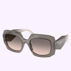 The PRADA Sunglasses 0PR B23S 20F70S54 feature large geometric translucent gray frames, gradient brown lenses, and the Prada logo on the temples, shown on a light lavender background for a sporty statement.