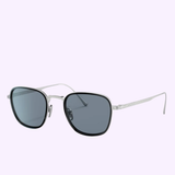 The Persol PO5007ST 800656 47 Unisex Sunglasses from the Persol Sunglasses titanium collection feature a silver metal frame, dark square lenses, thin arms, and adjustable nose pads, showcased on a light purple background.