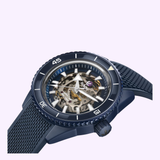 The Rado Watches Captain Cook High-Tech Ceramic Skeleton R32153209 features a blue skeleton design with a textured band, showcasing its inner gears through a transparent dial, set against a light purple background.