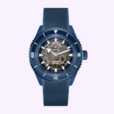 The Rado Watches Captain Cook High-Tech Ceramic Skeleton R32153209 features a blue case, textured strap, transparent skeleton dial showing internal gears, white bezel hour markers, and visible hands and logo on the face.