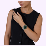 A person wears a silver Rado Watches Captain Cook R32223313 automatic watch with a green dial and a metal mesh band on their wrist.