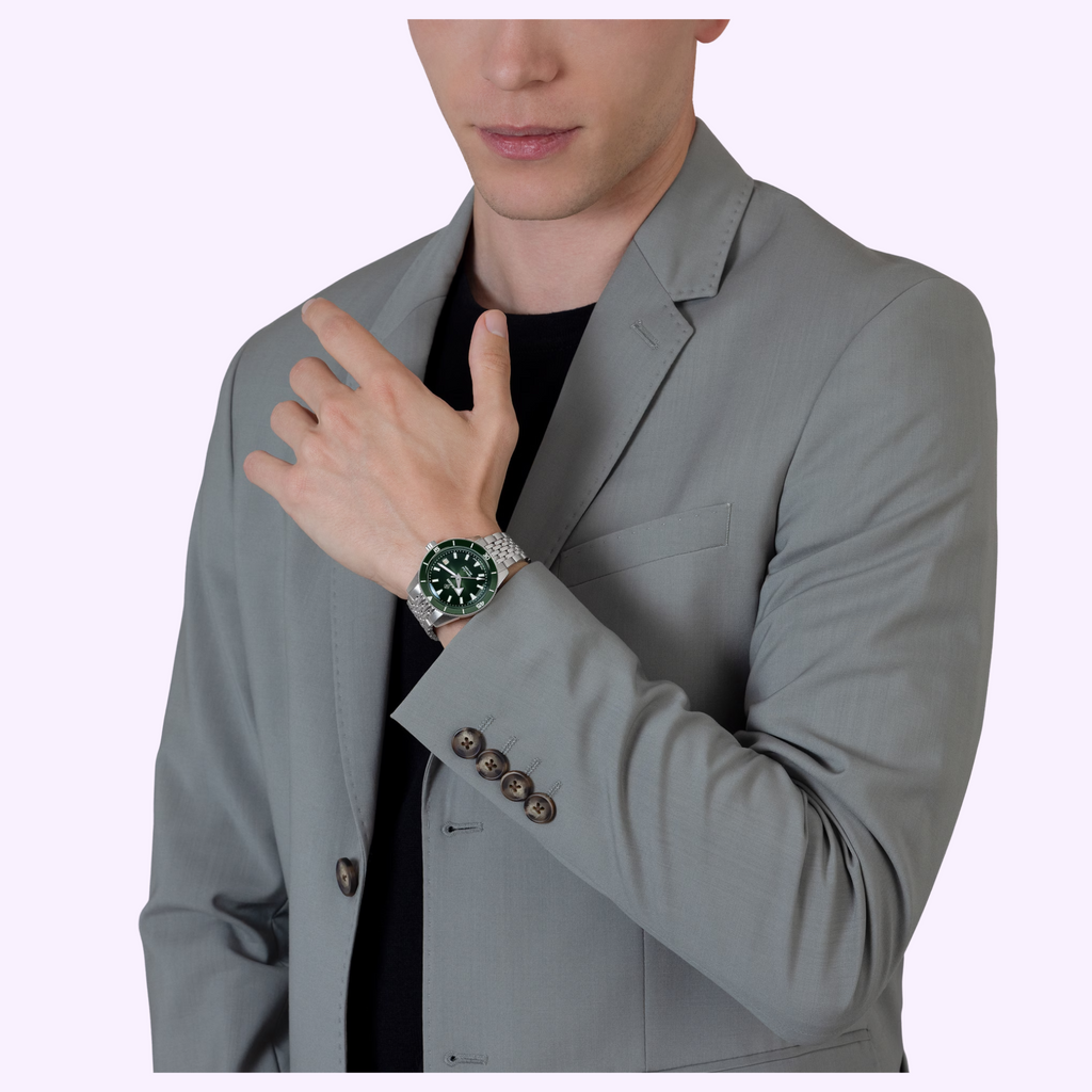 Man in a grey blazer wearing the Rado Captain Cook R32223313 with green dial and steel link bracelet