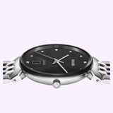A close-up side view of the Rado Watches Florence Diamonds R48912733 in stainless steel, featuring a black dial with diamond hour markers and a silver metal band, set against a light purple background.