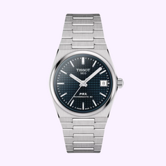 The Tissot Watches TISSOT T1372071104100 PRX Unisex PW80 SS BR BL IND 35MM watch features a stainless steel case and bracelet, black textured dial, silver hands and markers, date window at 3 o’clock, set against a light background.