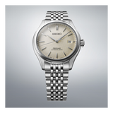 The Seiko Luxe Watches Presage Classic Series SPB463 features a silver stainless steel bracelet, textured cream dial, date at 3 o’clock, and silver markers and hands, displayed on a light gray gradient background.