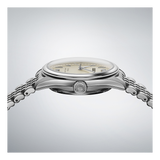 A close-up side view of the Seiko Luxe Watches Presage Classic Series SPB463 shows its silver metallic bracelet, cream dial, and an S-engraved crown. Set against a light gray gradient, the refined Japanese mechanical design is highlighted.