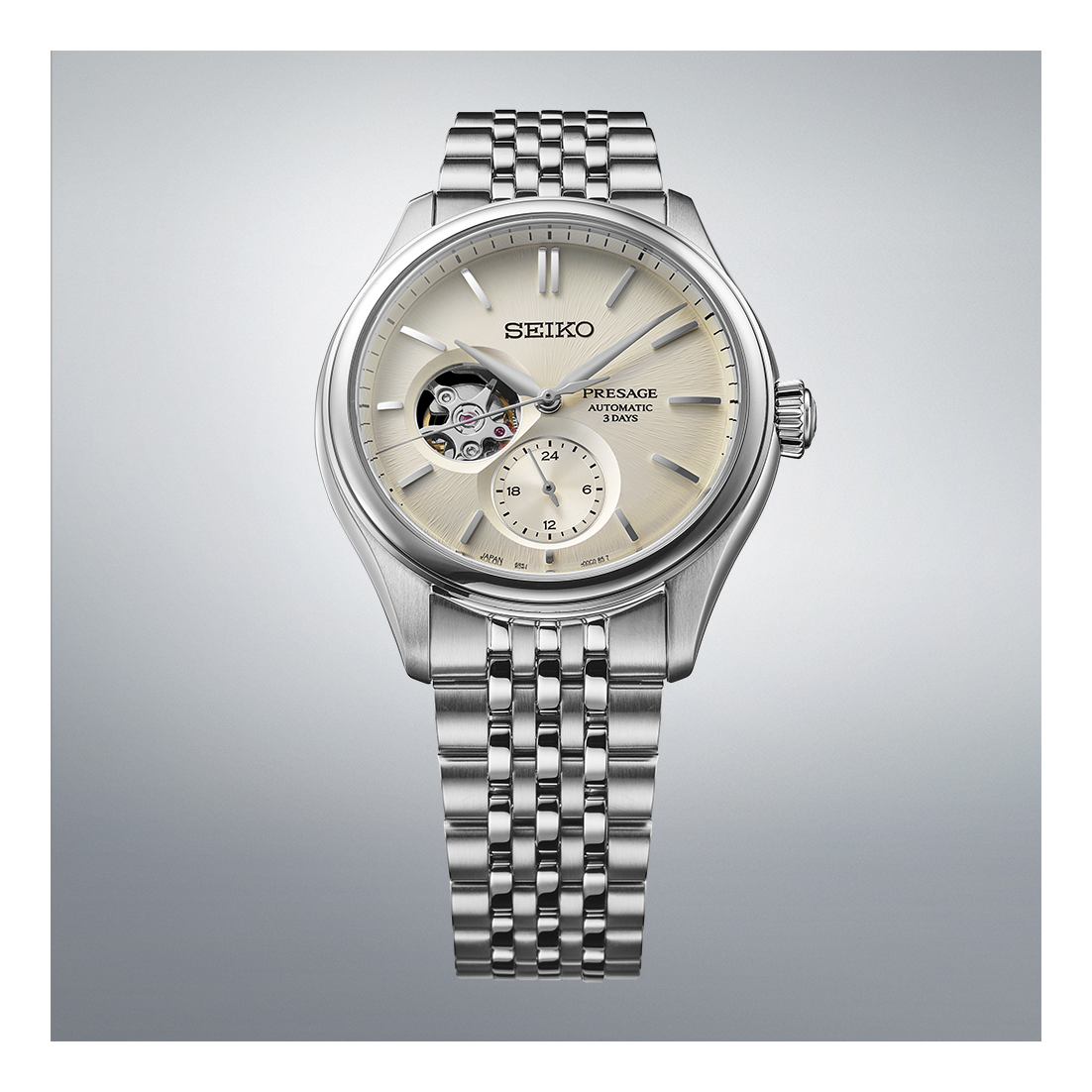 The Seiko Luxe Watches Presage Classic Series SPB469 features a beige dial with an open-heart display, silver hour markers, and a stainless steel bracelet, highlighted against a light gradient background.