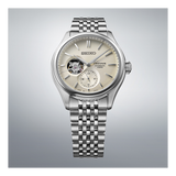 The Seiko Luxe Watches Presage Classic Series SPB469 features a beige dial with an open-heart display, silver hour markers, and a stainless steel bracelet, highlighted against a light gradient background.
