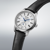 The Seiko Luxe Watches Presage Craftsmanship Series Enamel SPB495 features a white enamel dial with black Roman numerals, blue hands, a subdial above 6 o’clock, and a black leather strap in a stainless steel case.