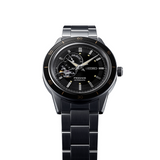 The Seiko Watches SSA425 Presage Style60's men’s watch features a black dial with metallic hour markers, open-heart design, and a stainless steel strap, displayed against a white background.