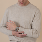 A person in a beige sweater looks down at their wrist, showcasing the Rado Watches Anatom Automatic Skeleton R10206109 with a brown leather strap against a neutral background.