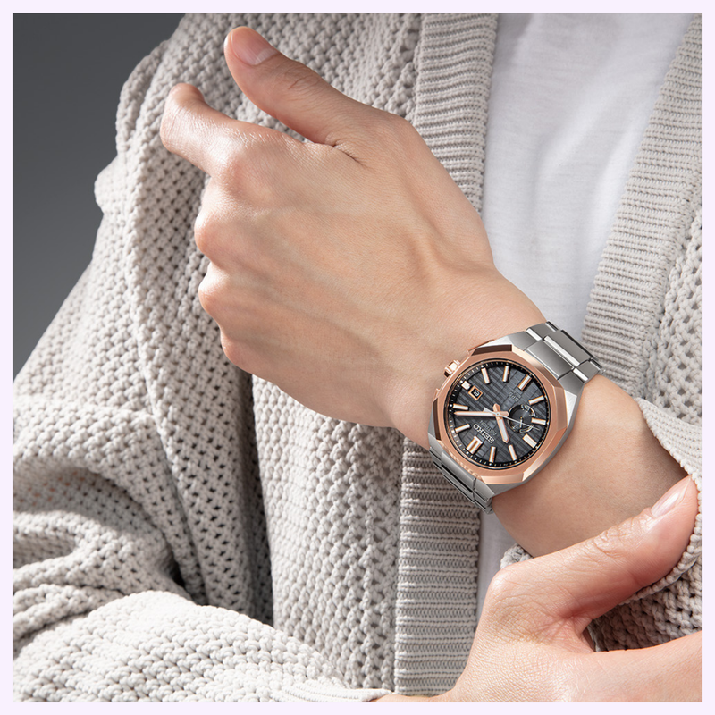 Seiko Astron SSJ014 On the Wrist Person in a beige cardigan adjusting a Seiko Astron GPS Solar SSJ014 with gray dial and rose gold-tone bezel on the wrist