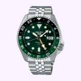 Seiko Luxe Watches’ SSK035 Sports SKX Style GMT features a silver metal band, green dial, green/black bezel, white and yellow markers, date at 3 o’clock, “Automatic GMT” text, and classic sports styling on a light background.