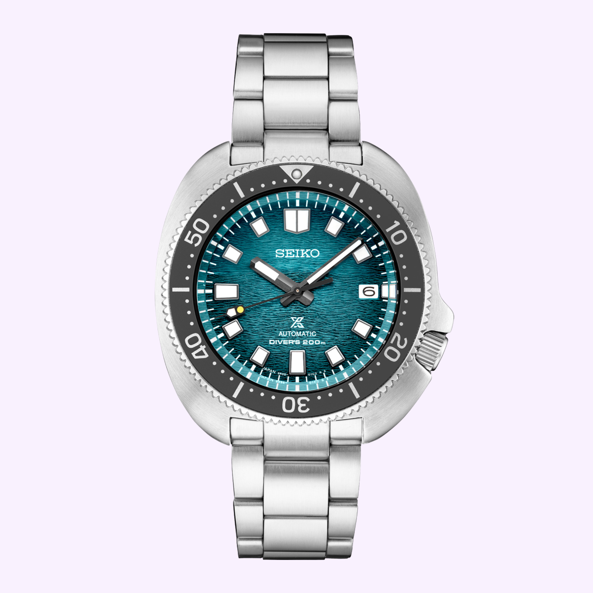 The Seiko Luxe Watches PROSPEX BUILT FOR THE ICE DIVER U.S. SPECIAL EDITION SPB265 features a stainless steel case, turquoise textured dial with white markers, date at 3 o’clock, and black rotating bezel, set against a light purple background.