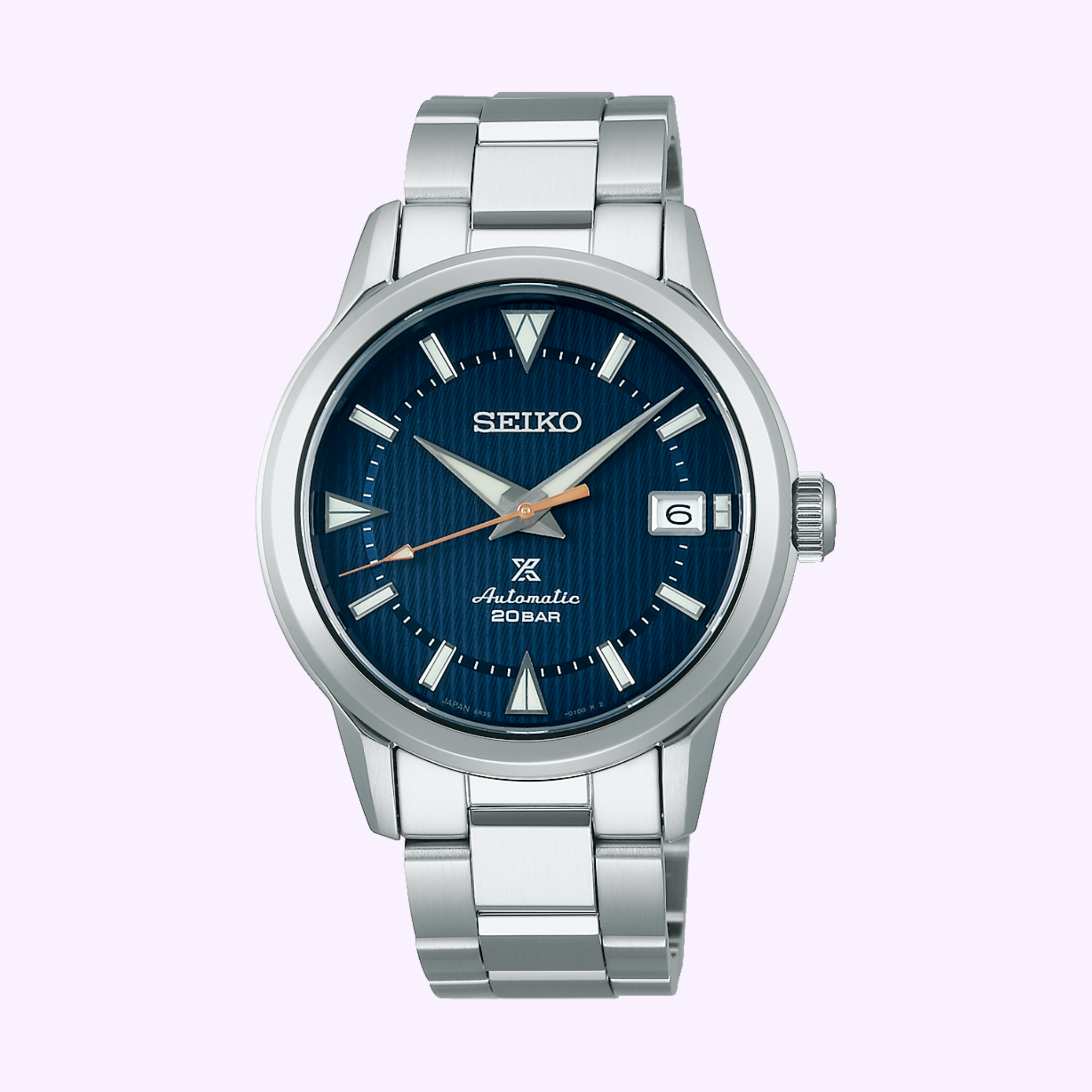 The Seiko Luxe Watches PROSPEX SPB249 features a stainless steel case, blue textured dial with silver hour markers, date window at 3 o’clock, and Automatic 20BAR above 6 o’clock, shown on a light purple background.