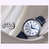 A Seiko Luxe Watches Presage Classic Series HCC004 Limited Edition with silver dial and blue leather strap is displayed on a light background. "145th Anniversary" and a swirl decorate the left side, highlighting this exclusive watch.
