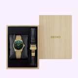 A Seiko Luxe Watches gift set showcasing the Presage Classic Series HCC009 Limited Edition automatic watch, distinguished by its gold case and vibrant green dial, complete with an extra black leather strap and presented in a light wooden box featuring the SEIKO logo on the lid—all expertly crafted to reflect refined Japanese artistry and displayed against a soft background.